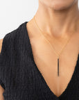 Woman wearing a black diamond gold necklace.