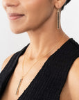 Woman wearing black diamond gold earrings and black diamond gold necklace on a white background