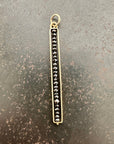 Gold pendant with black diamond beads on a gray surface