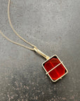 14k gold Necklace with a carnelian pendant on a gray surface