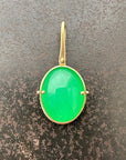 An oval pendant featuring a vibrant green chrysoprase gemstone in a gold bezel setting with a gold hook, displayed on a textured dark gray background.