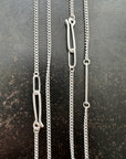 silver curb chains on a dark textured surface
