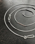 silver curb chains on a dark textured surface