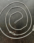 silver curb chains on a dark textured surface