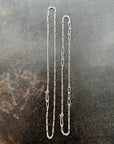 Silver figaro chain necklace on a textured dark surface