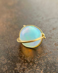 An ethiopian opal orb pendant in an 18k gold setting