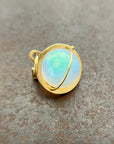An ethiopian opal orb pendant in an 18k gold setting