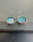 Pair of opal stud earrings on a dark surface