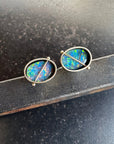 Pair of opal stud earrings on a dark surface
