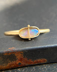 Gold ring with an opal gemstone on a dark surface