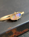 Gold ring with an opal gemstone on a dark surface