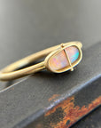 Gold ring with an opal gemstone on a dark surface