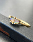 Gold ring with an opal gemstone on a dark surface