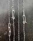 silver paperclip chains with clasp on a dark textured background