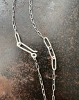 silver paperclip chains with clasp on a dark textured background