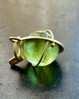 An 18k gold orb pendant with a green peridot sphere gemstone.