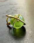An 18k gold orb pendant with a green peridot sphere gemstone.