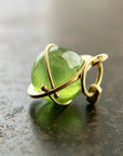 An 18k gold orb pendant with a green peridot sphere gemstone.
