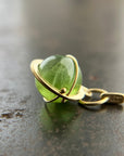 An 18k gold orb pendant with a green peridot sphere gemstone.