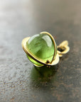 An 18k gold orb pendant with a green peridot sphere gemstone.