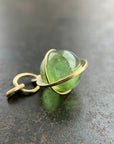 An 18k gold orb pendant with a green peridot sphere gemstone.