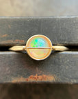 Gold ring with an opal stone on a wooden surface