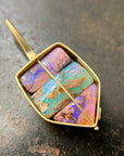A shield-shaped pendant featuring an 18k gold frame and three rectangular inlay wood replacement opals in pink, turquoise, purple, and brown.