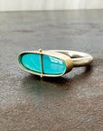 Silver and gold ring with a turquoise stone on a gray surface