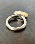 Silver and gold ring with a turquoise stone on a gray surface