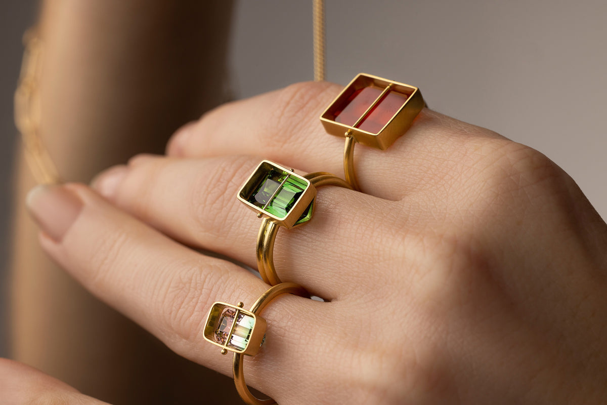 hand wearing tourmaline and carnelian rings