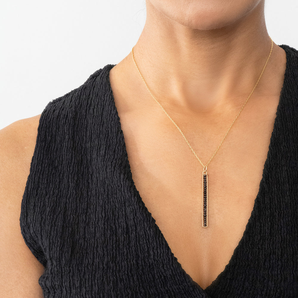 Woman wearing a black diamond gold necklace.