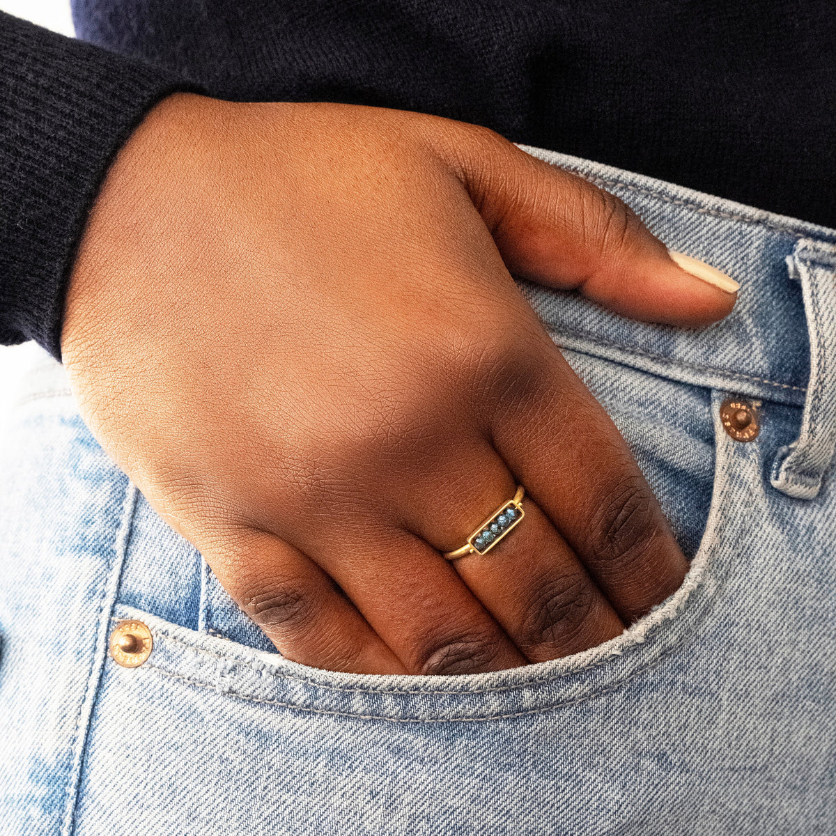 Hand with a blue diamond gold ring in a pocket of blue jeans