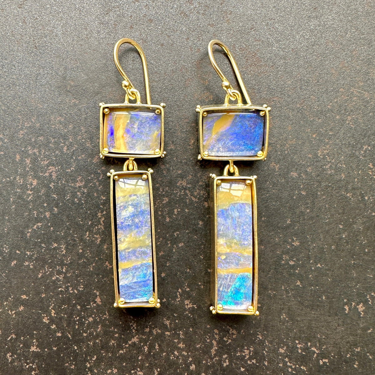 boulder opal earrings with purple and golden stripes Captured in 18k gold frames