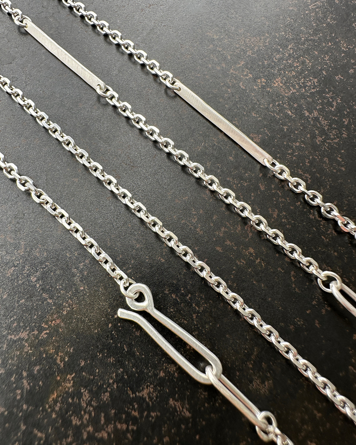 Silver diamond cut cable chain necklace on a textured dark surface