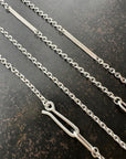 Silver diamond cut cable chain necklace on a textured dark surface