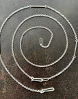 Silver chain necklace on a textured dark surface