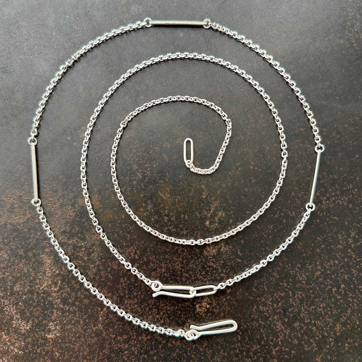 Silver diamond cut cable chain necklace on a textured dark surface