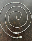 Silver diamond cut cable chain necklace on a textured dark surface