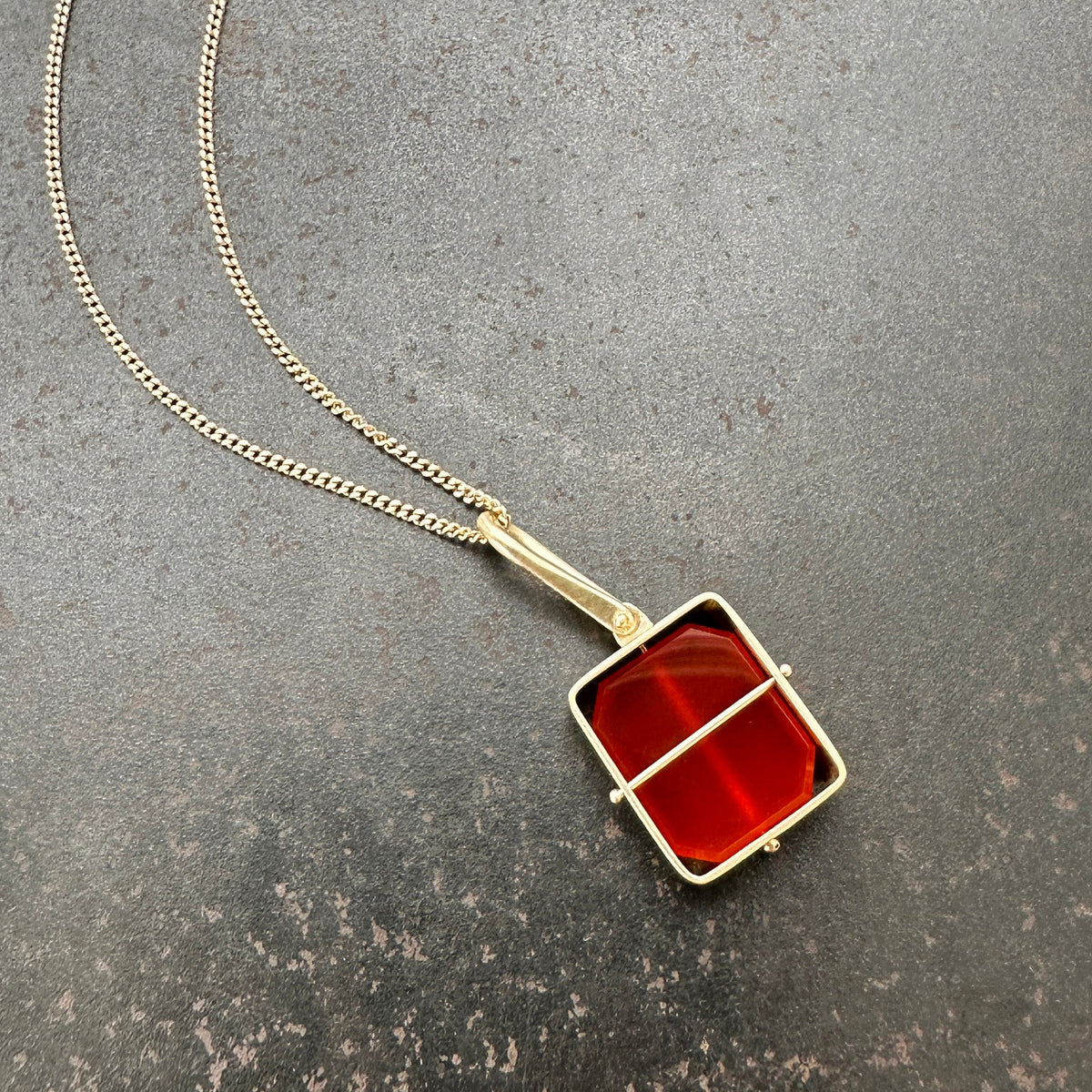 14k gold Necklace with a carnelian pendant on a gray surface