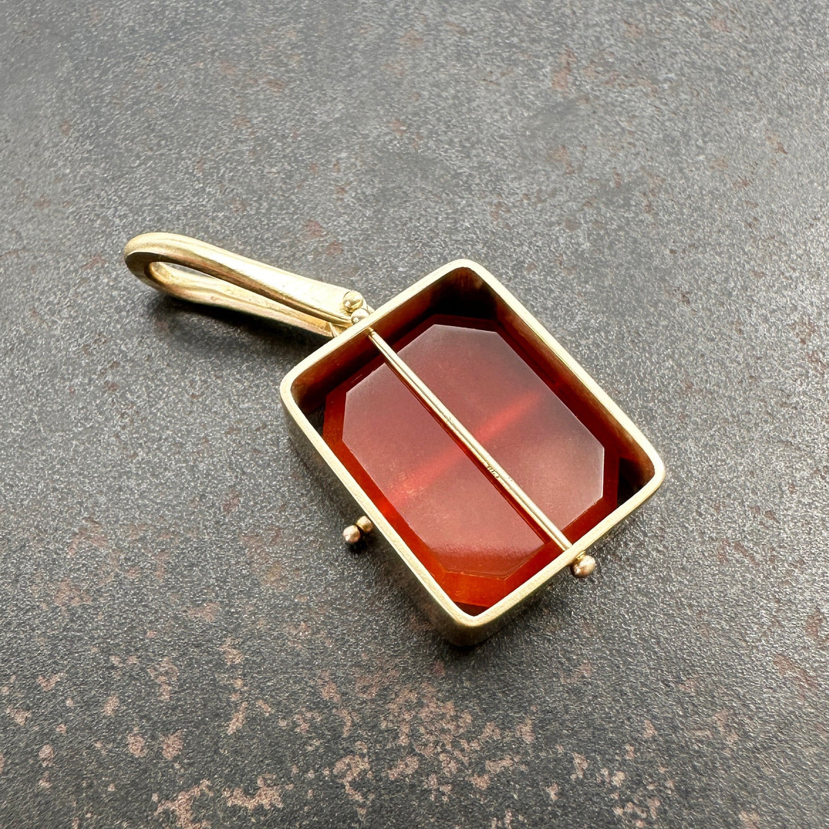 14k carnelian pendant on a gray surface