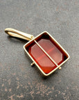 14k carnelian pendant on a gray surface