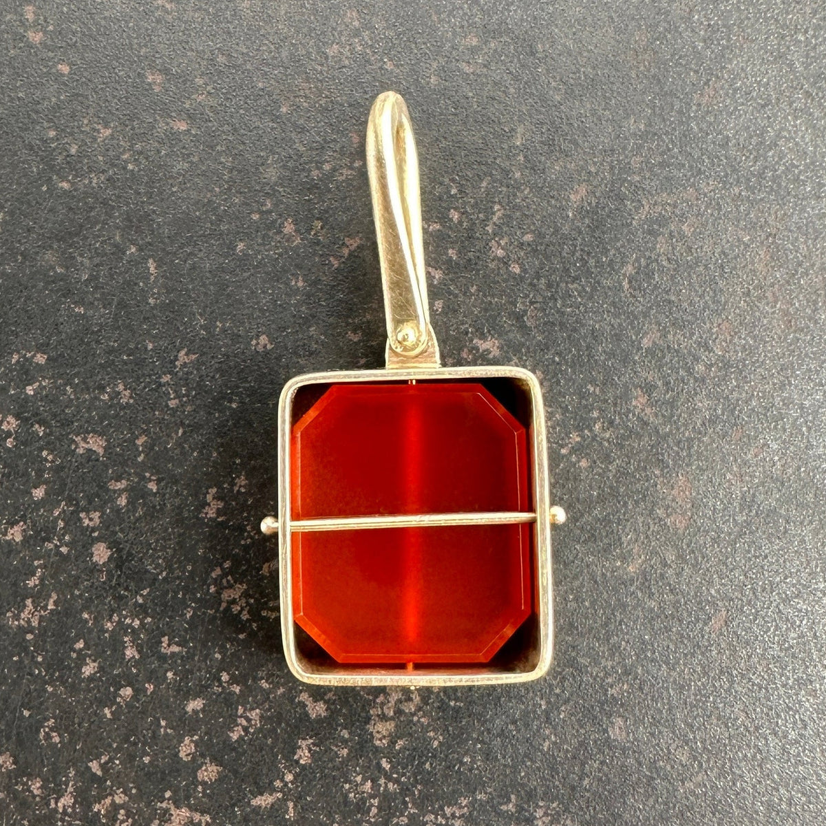 14k gold carnelian pendant on a gray surface