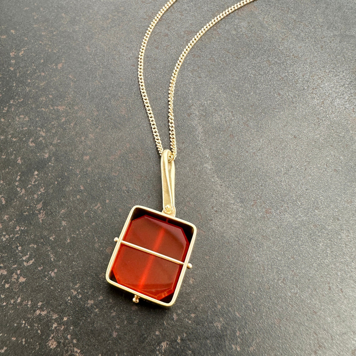 14k gold Necklace with a carnelian pendant on a gray surface