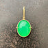 An oval pendant featuring a vibrant green chrysoprase gemstone in a gold bezel setting with a gold hook, displayed on a textured dark gray background.