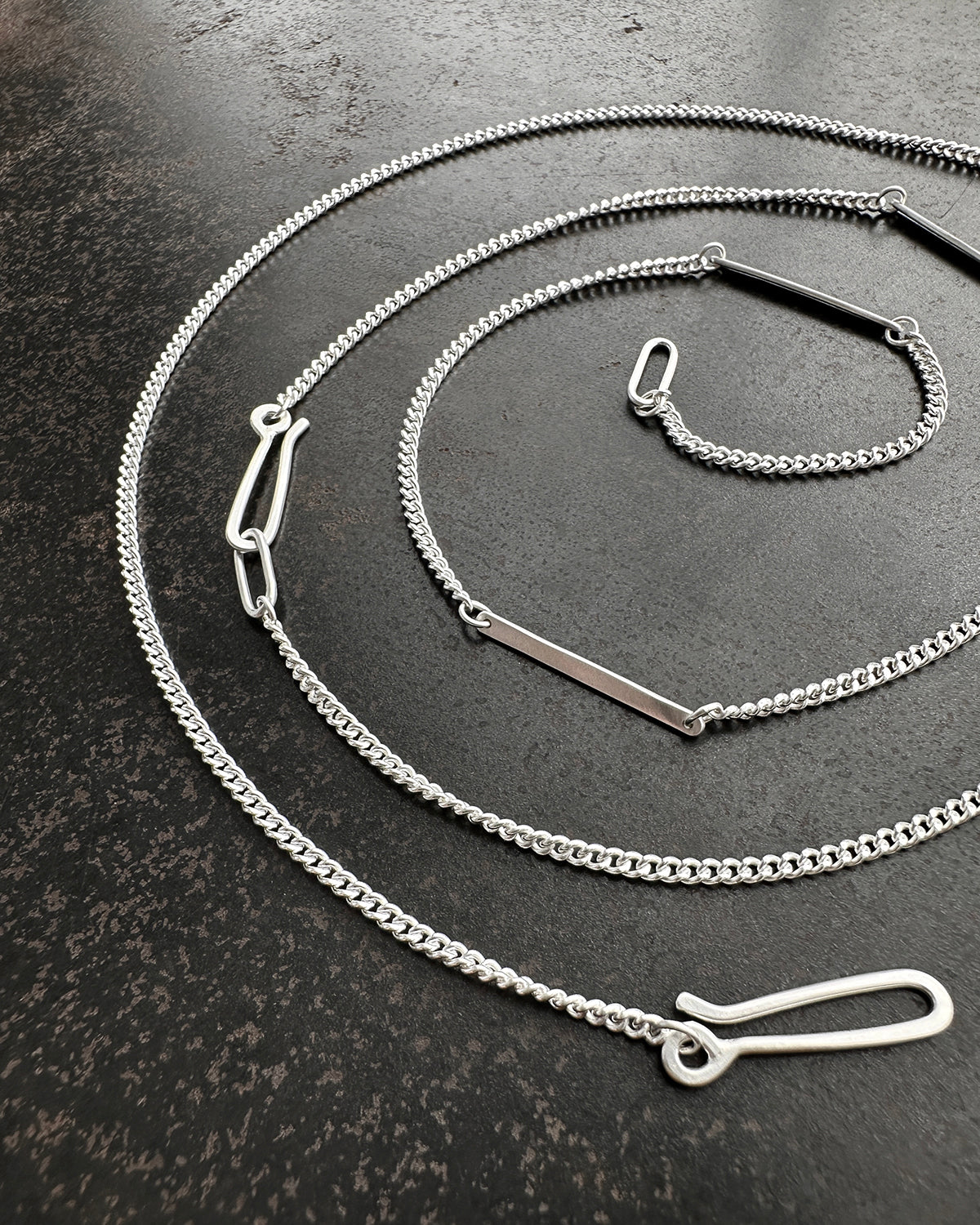 silver curb chains on a dark textured surface