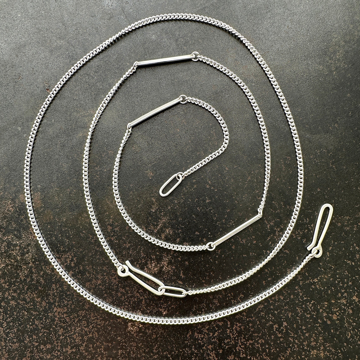 silver curb chains on a dark textured surface
