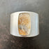 Silver cuff bracelet with a dendritic agate stone inlay on a gray surface