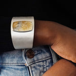 Silver cuff bracelet with a dendritic agate stone inlay on a gray surface
