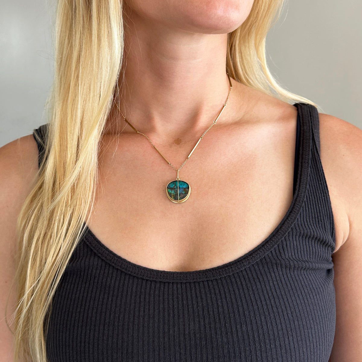 Model wearing gold pendant with two boulder opals