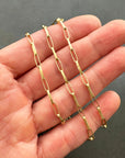 An 18k gold elongated oval chain necklace coiled in a spiral on a hand.